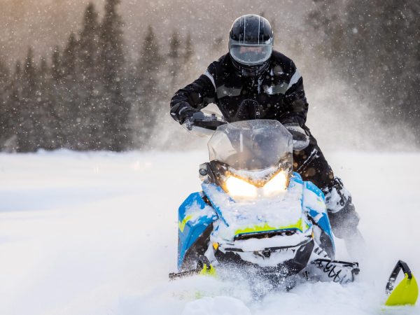 Man having fun speeding with a snowmobile through the fresh powder snow at sunset in the Laurentians Mountains, Quebec, Canada

motoneige